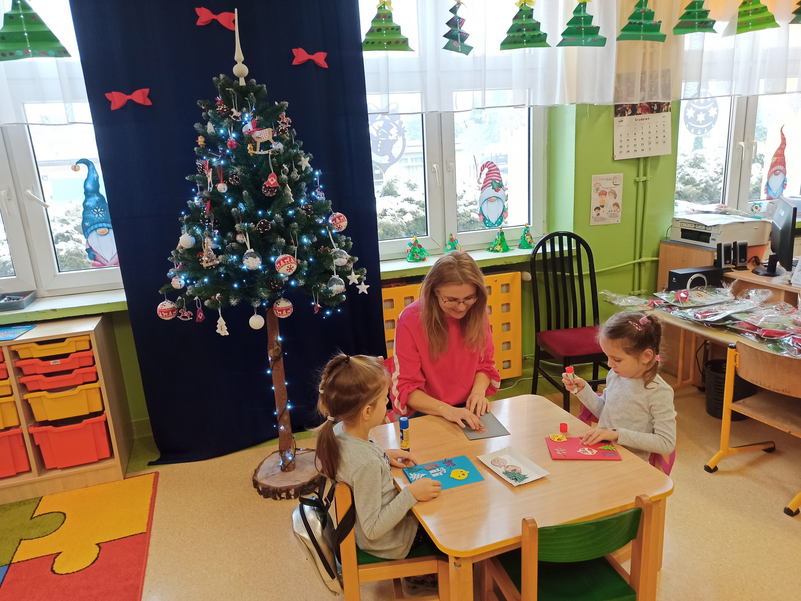 Dzieci wraz z bibliotekarką wykonują świąteczne prace plastyczne.