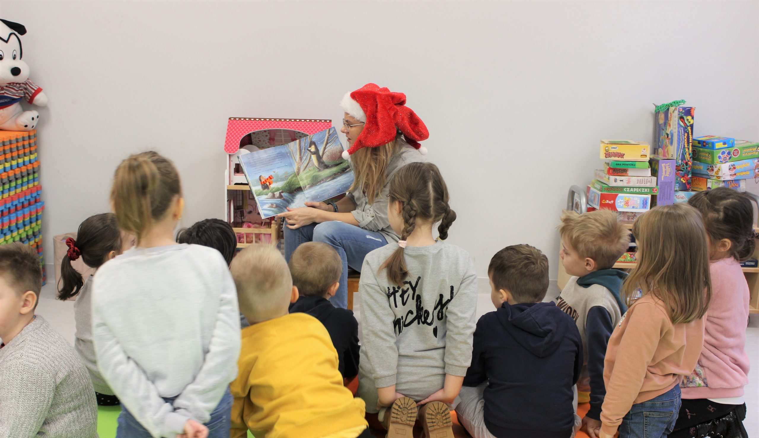 Bibliotekarka czyta dzieciom książkę w ramach warsztatów świątecznych w bibliotece.